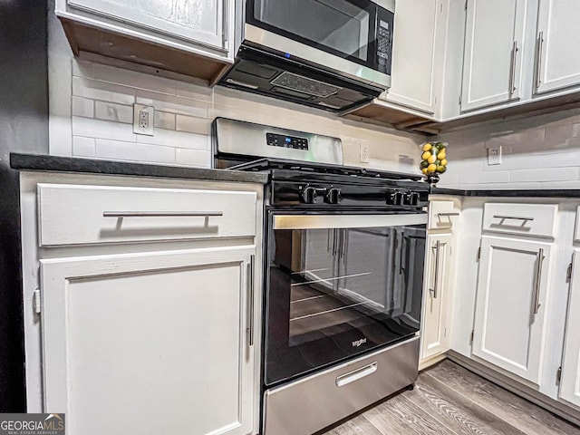 3150 Stratford Green Pl, Avondale Estates, GA 30002 - kitchen featuring stainless steel appliances, dark countertops, light wood finished floors, white cabinetry, and tasteful backsplash