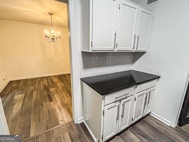 3150 Stratford Green Pl, Avondale Estates, GA 30002 - kitchen with dark wood finished floors, dark countertops, white cabinetry, and a chandelier