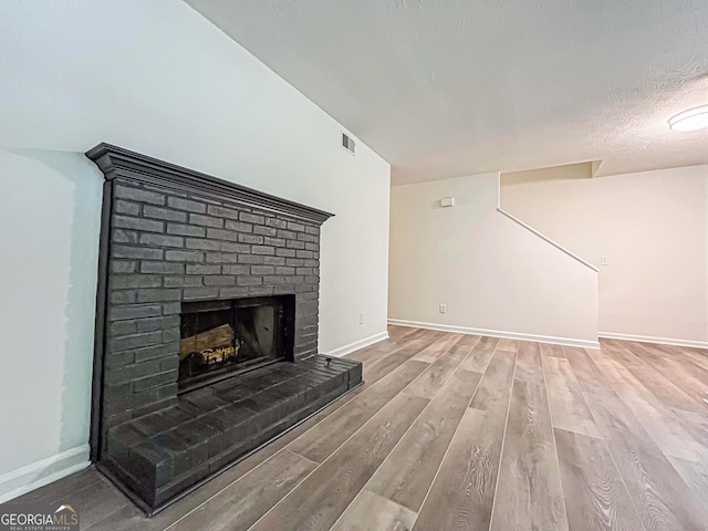 3150 Stratford Green Pl, Avondale Estates, GA 30002 - unfurnished living room featuring wood finished floors, a brick fireplace, and a textured ceiling