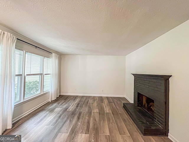 3150 Stratford Green Pl, Avondale Estates, GA 30002 - unfurnished living room featuring dark wood-style flooring, a brick fireplace, and a textured ceiling