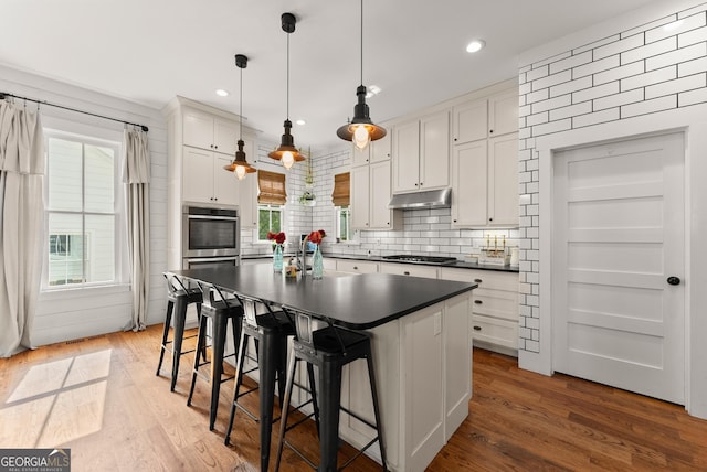 429 Hubert Harris Rd, Cornelia, GA 30531 - kitchen with dark countertops, gas cooktop, under cabinet range hood, white cabinetry, and wood finished floors