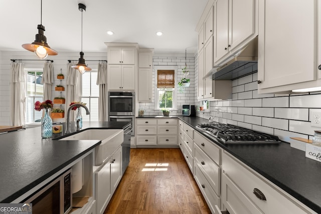 429 Hubert Harris Rd, Cornelia, GA 30531 - kitchen featuring stainless steel appliances, dark countertops, under cabinet range hood, decorative backsplash, and pendant lighting