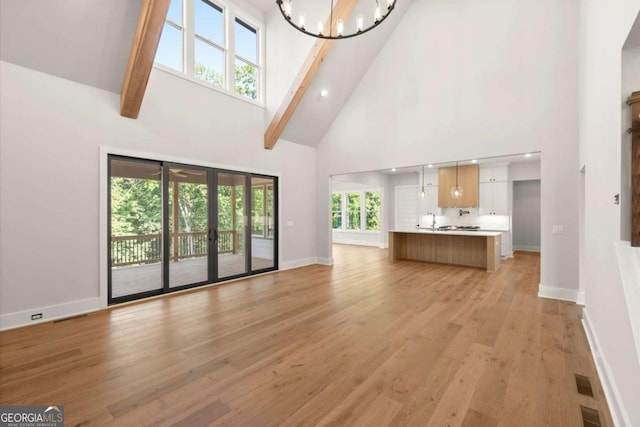 6750 Pannell Rd, Buford, GA 30518 - unfurnished living room featuring high vaulted ceiling, a chandelier, light wood finished floors, beamed ceiling, and french doors
