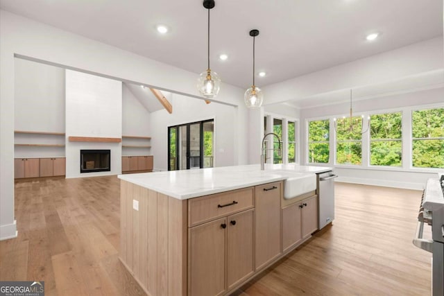 6750 Pannell Rd, Buford, GA 30518 - kitchen with appliances with stainless steel finishes, light wood finished floors, a fireplace, light countertops, and a center island with sink