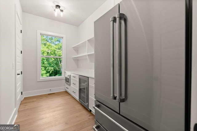 6750 Pannell Rd, Buford, GA 30518 - kitchen with freestanding refrigerator, wine cooler, light countertops, light wood-style flooring, and open shelves