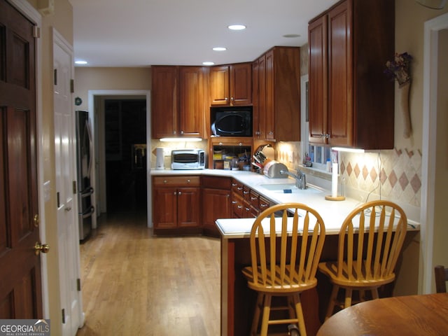 4098 Nancy Creek Way NE, Brookhaven, GA 30319 - kitchen with a peninsula, light countertops, tasteful backsplash, light wood-style flooring, and a kitchen breakfast bar