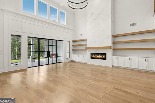 3735 Hamilton Mill Rd, Buford, GA 30519 - unfurnished living room with a towering ceiling, light wood-style flooring, plenty of natural light, a large fireplace, and a chandelier