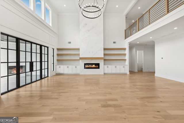 3735 Hamilton Mill Rd, Buford, GA 30519 - unfurnished living room with a towering ceiling, a fireplace, a chandelier, light wood-type flooring, and crown molding