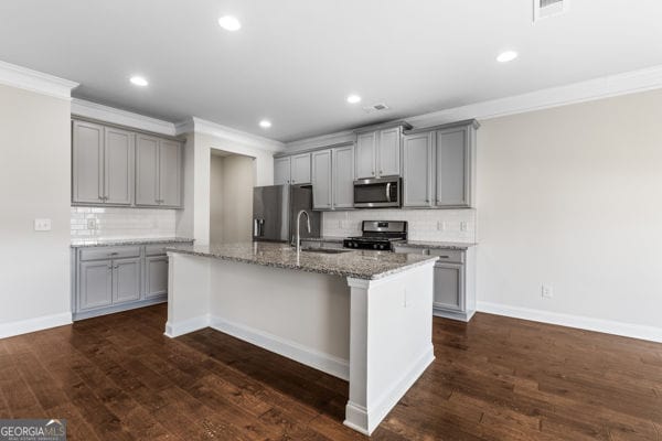 1494 Weeping Tree Cir, Hoschton, GA 30548 - kitchen with stainless steel appliances, gray cabinetry, ornamental molding, tasteful backsplash, and a kitchen island with sink
