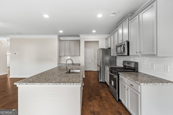 1494 Weeping Tree Cir, Hoschton, GA 30548 - kitchen featuring appliances with stainless steel finishes, backsplash, a kitchen island with sink, light stone counters, and recessed lighting
