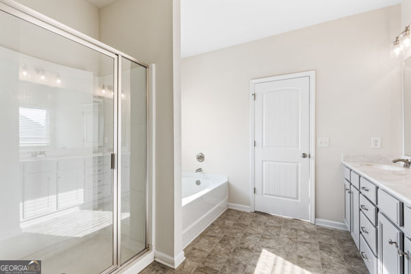 1494 Weeping Tree Cir, Hoschton, GA 30548 - full bath with double vanity, a garden tub, and a stall shower