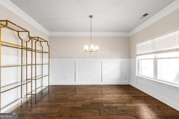 1494 Weeping Tree Cir, Hoschton, GA 30548 - unfurnished dining area featuring a chandelier, hardwood / wood-style flooring, crown molding, wainscoting, and a decorative wall