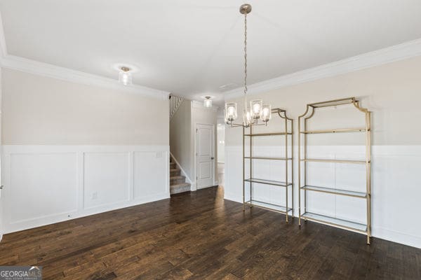 1494 Weeping Tree Cir, Hoschton, GA 30548 - unfurnished room featuring crown molding, a wainscoted wall, stairway, a chandelier, and dark wood finished floors