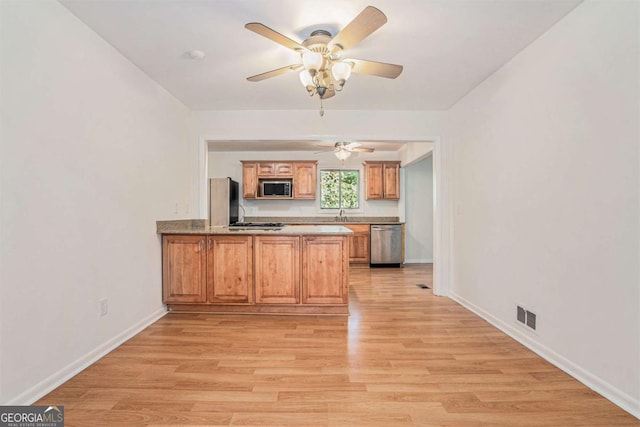 1260 Fork Creek Trl, Decatur, GA 30033 - kitchen featuring stainless steel appliances, a peninsula, light wood-type flooring, a ceiling fan, and brown cabinets