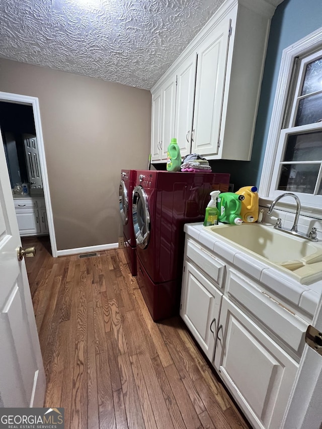 186 Kingston Rd, Colbert, GA 30628 - laundry area featuring separate washer and dryer, wood finished floors, cabinet space, and a textured ceiling