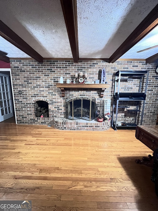 186 Kingston Rd, Colbert, GA 30628 - unfurnished living room featuring a fireplace, hardwood / wood-style floors, beam ceiling, and a textured ceiling