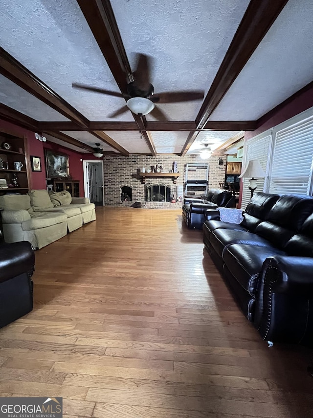 186 Kingston Rd, Colbert, GA 30628 - living area featuring a ceiling fan, hardwood / wood-style flooring, beamed ceiling, a brick fireplace, and a textured ceiling