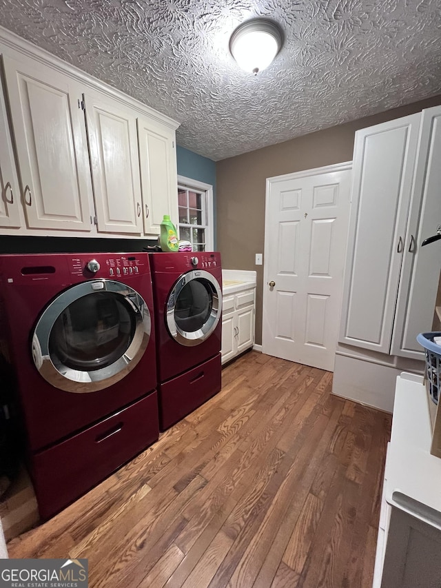 186 Kingston Rd, Colbert, GA 30628 - laundry area with cabinet space, washer and clothes dryer, light wood-type flooring, and a textured ceiling