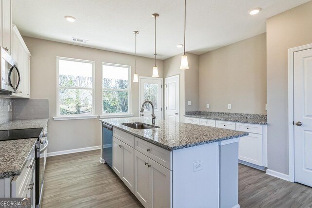 105 Ivy Glen Dr, Perry, GA 31069 - kitchen with appliances with stainless steel finishes, light wood finished floors, white cabinets, a kitchen island with sink, and light stone countertops