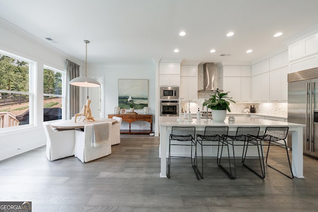 15755 Burdette Ct, Milton, GA 30004 - kitchen featuring built in appliances, wall chimney exhaust hood, an island with sink, decorative backsplash, and recessed lighting