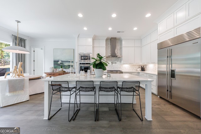 15755 Burdette Ct, Milton, GA 30004 - kitchen featuring built in appliances, wall chimney exhaust hood, ornamental molding, a center island with sink, and tasteful backsplash