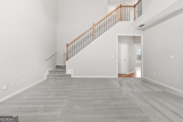 8750 Redford Ln, Suwanee, GA 30024 - unfurnished living room with a high ceiling, carpet flooring, and stairway