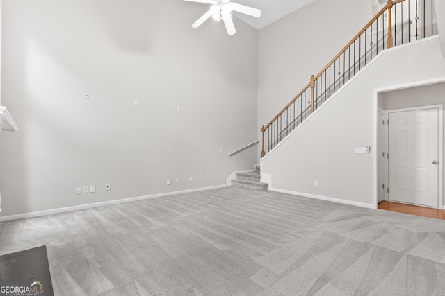 8750 Redford Ln, Suwanee, GA 30024 - unfurnished living room with a ceiling fan, carpet flooring, stairway, and a towering ceiling