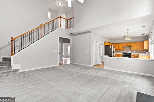 8750 Redford Ln, Suwanee, GA 30024 - unfurnished living room featuring light carpet, plenty of natural light, a towering ceiling, and stairway