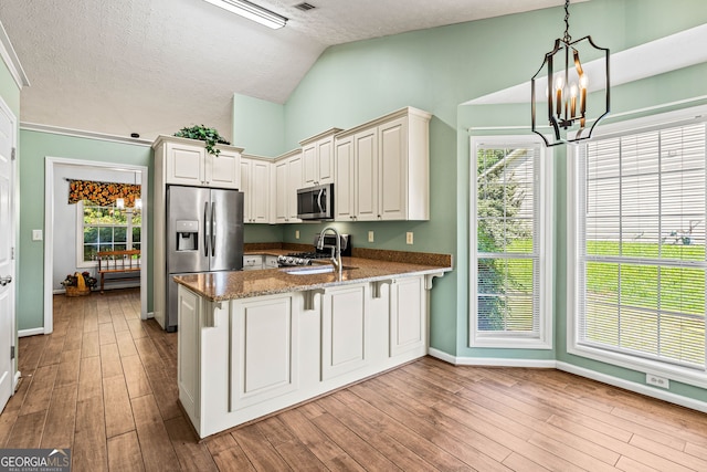 5832 Sycamore Ridge Dr, Sugar Hill, GA 30518 - kitchen featuring stainless steel appliances, vaulted ceiling, a peninsula, a chandelier, and dark stone counters