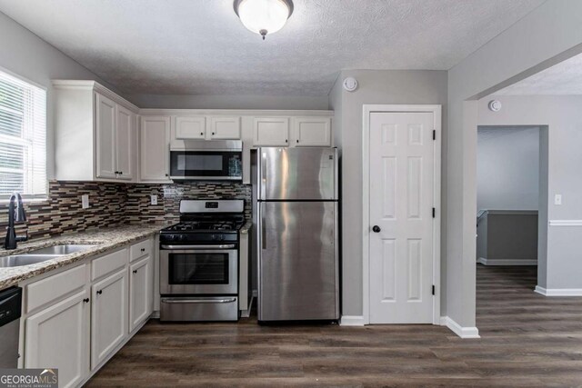 1404 Lancaster Ct, Mcdonough, GA 30252 - kitchen featuring appliances with stainless steel finishes, white cabinetry, light stone counters, decorative backsplash, and dark wood-type flooring
