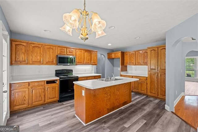 2333 Old Newnan Rd, Carrollton, GA 30116 - kitchen with black electric range oven, stainless steel microwave, arched walkways, brown cabinetry, and light countertops