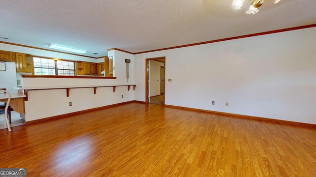 26 Ben Blvd, Swainsboro, GA 30401 - unfurnished living room featuring light wood-type flooring, ornamental molding, a chandelier, and a textured ceiling