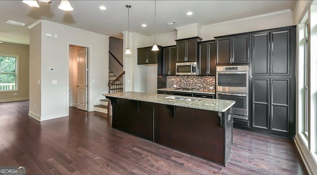1306 Harris Way, Brookhaven, GA 30319 - kitchen featuring stainless steel appliances, decorative backsplash, dark wood finished floors, light stone countertops, and a kitchen island with sink