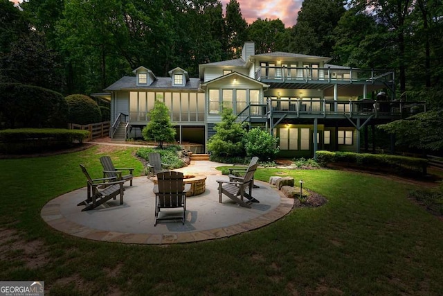 627 Apache Trl, Woodstock, GA 30189 - back of property at dusk with a fire pit, stairway, a lawn, a patio, and a chimney