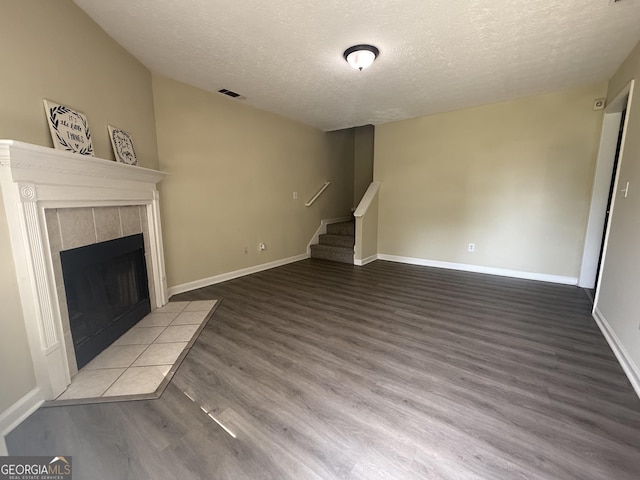 756 Glenshire Ct, Riverdale, GA 30274 - unfurnished living room with a textured ceiling, stairs, wood finished floors, and a tile fireplace