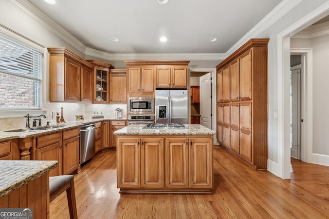 3410 Enclave Mill Ct, Dacula, GA 30019 - kitchen with stainless steel appliances, light stone countertops, light wood-style flooring, a kitchen island, and crown molding