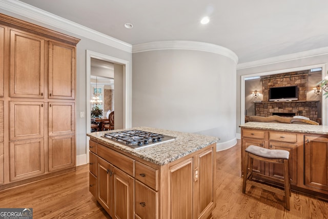 3410 Enclave Mill Ct, Dacula, GA 30019 - kitchen featuring stainless steel gas stovetop, light wood finished floors, light stone counters, ornamental molding, and open floor plan