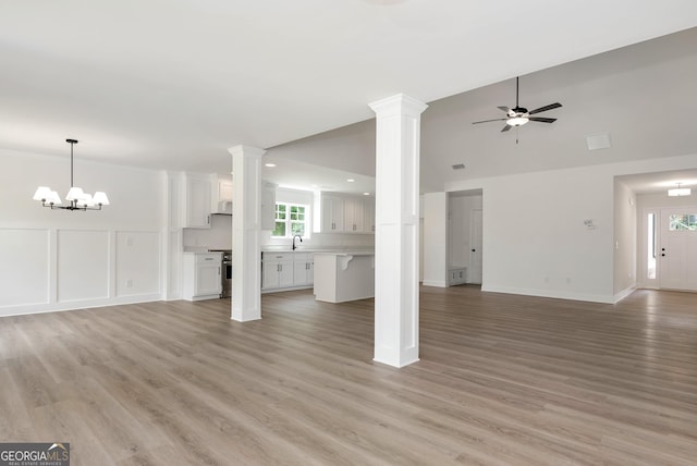 797 Ode Peppers Rd, Winder, GA 30680 - unfurnished living room featuring a ceiling fan, light wood-type flooring, decorative columns, a chandelier, and vaulted ceiling
