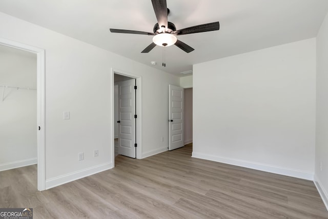 797 Ode Peppers Rd, Winder, GA 30680 - unfurnished bedroom with a walk in closet, light wood-style flooring, a closet, and a ceiling fan