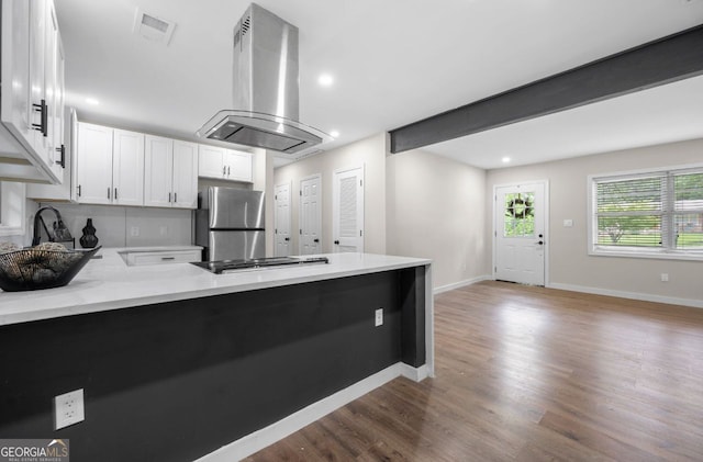 6402 Kensington Ct, Austell, GA 30106 - kitchen featuring island exhaust hood, freestanding refrigerator, a peninsula, white cabinets, and wood finished floors