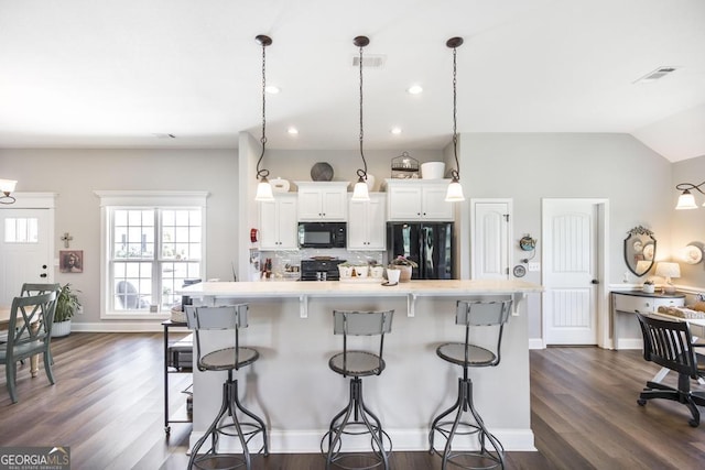 2303 Quail Ridge Ln, Perry, GA 31069 - kitchen with black appliances, a breakfast bar area, light countertops, backsplash, and dark wood finished floors