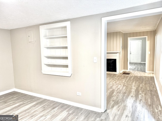 708 Degroat St, Lagrange, GA 30241 - empty room with wood finished floors, a fireplace, electric panel, a textured ceiling, and built in features