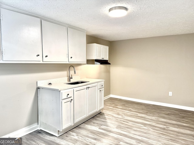 708 Degroat St, Lagrange, GA 30241 - kitchen with a textured ceiling, light wood finished floors, white cabinets, and light countertops