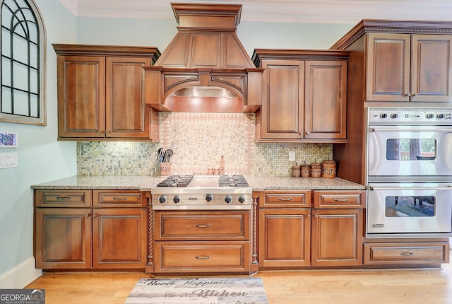 805 Cog Hl, Mcdonough, GA 30253 - kitchen featuring appliances with stainless steel finishes, custom range hood, light stone countertops, light wood-style floors, and crown molding