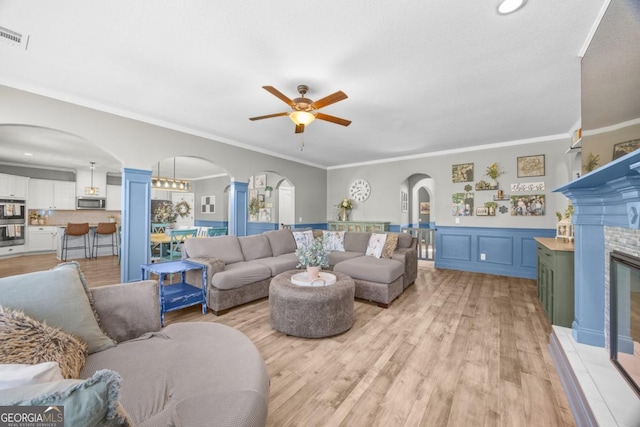 89 Crestview Dr, Guyton, GA 31312 - living room featuring arched walkways, a ceiling fan, ornamental molding, a wainscoted wall, and light wood-type flooring