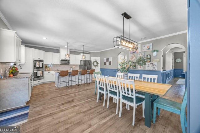 89 Crestview Dr, Guyton, GA 31312 - dining area featuring arched walkways, ornamental molding, light wood-style flooring, wainscoting, and recessed lighting