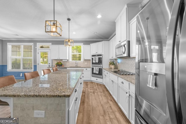 89 Crestview Dr, Guyton, GA 31312 - kitchen featuring stainless steel appliances, light wood finished floors, a center island, backsplash, and a breakfast bar area
