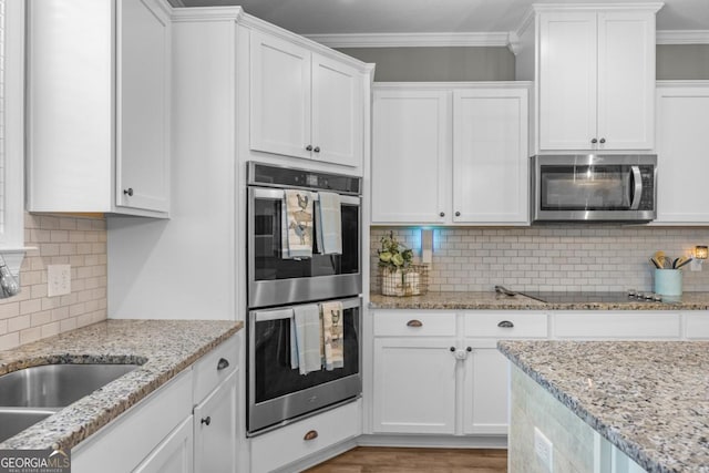89 Crestview Dr, Guyton, GA 31312 - kitchen featuring appliances with stainless steel finishes, white cabinets, decorative backsplash, and crown molding