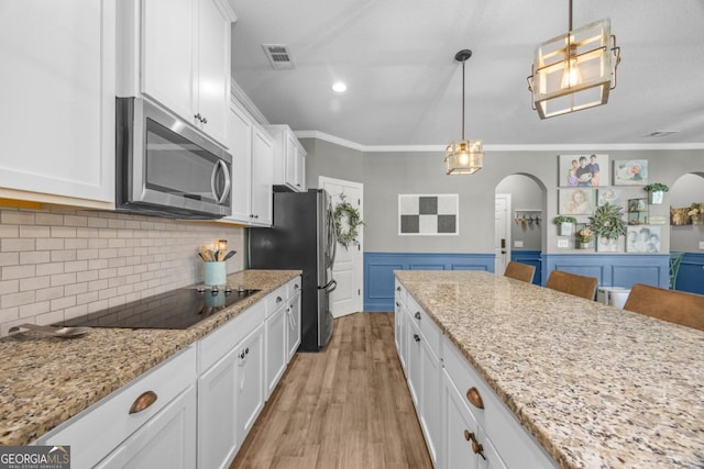 89 Crestview Dr, Guyton, GA 31312 - kitchen with stainless steel appliances, arched walkways, ornamental molding, white cabinetry, and light wood finished floors