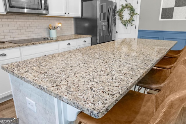 89 Crestview Dr, Guyton, GA 31312 - kitchen featuring stainless steel appliances, a center island, tasteful backsplash, light stone counters, and a wainscoted wall